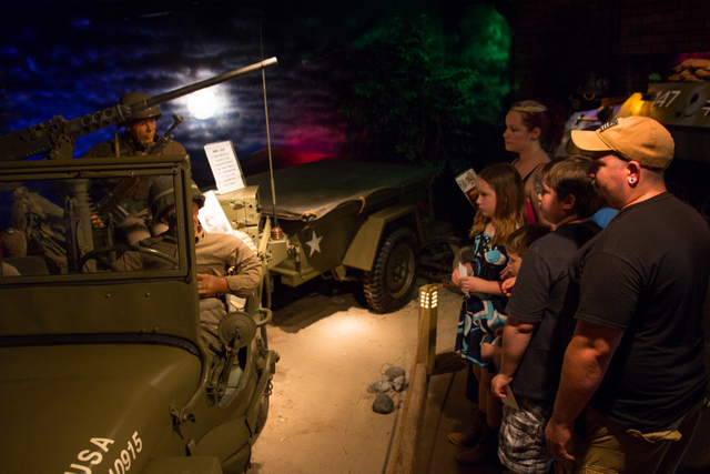 Visitors viewing a World War II–era military jeep and soldier figure at a Volo Fun museum military exhibit