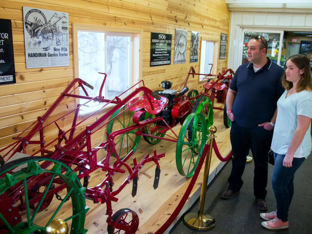 Visitors observing vintage tractors display.