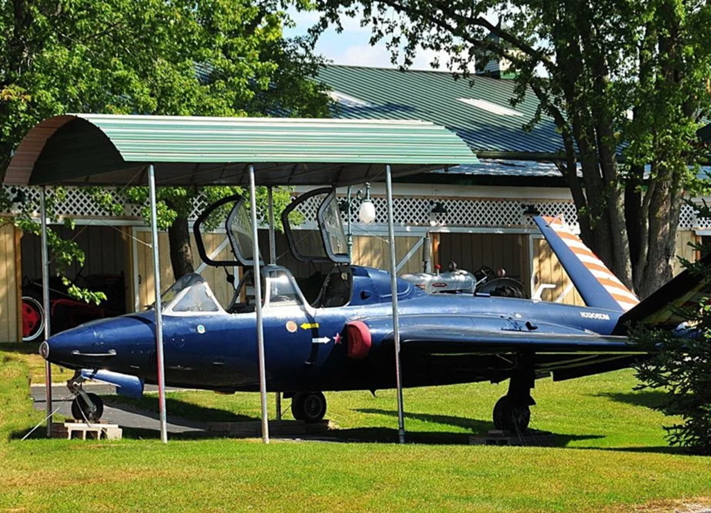 Vintage fire truck with shiny red paint and chrome details displayed outdoors on a paved surface, showing its classic front grill, headlights, and large wheels.