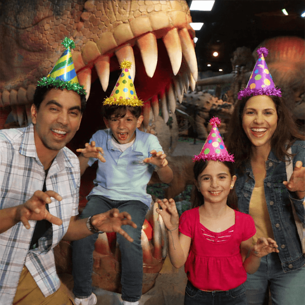 Family celebrating with dinosaur backdrop.