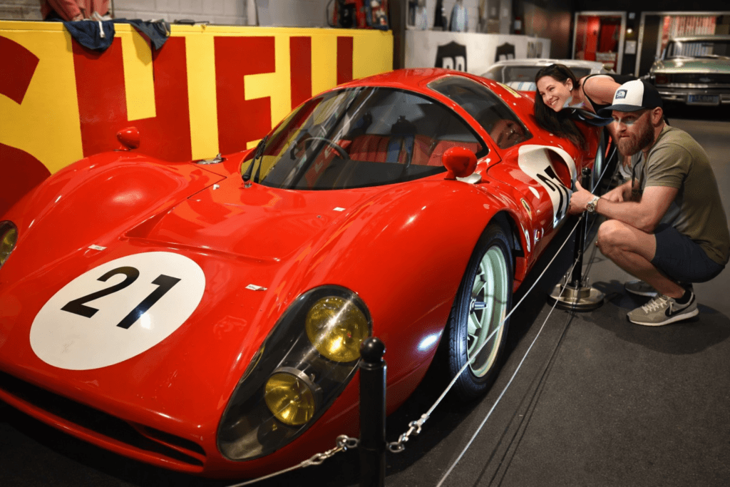 Couple posing with vintage red race car