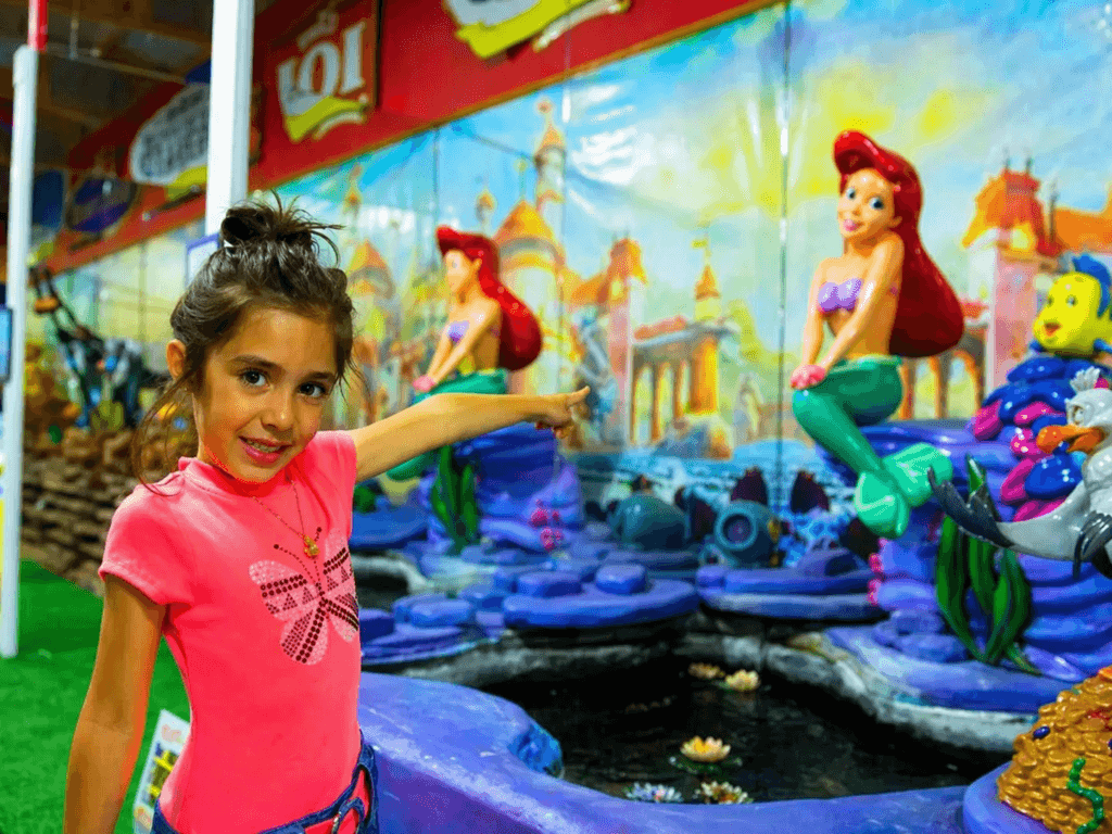 Girl pointing at colorful mermaid mural