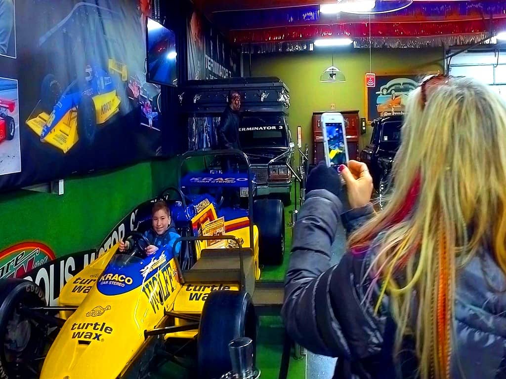 Child in race car, adult taking photo