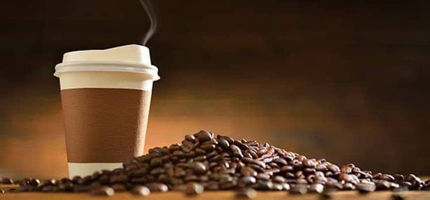 Coffee cup with scattered coffee beans