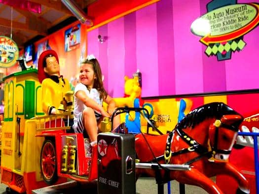 Colorful kiddie ride with bright lights and playful design at an amusement area
