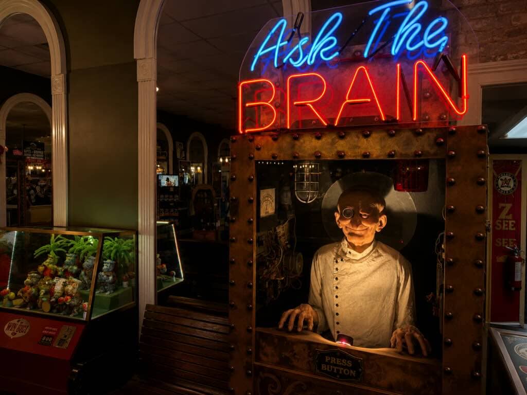 Vintage arcade machine with eerie figure Ask The Brain
